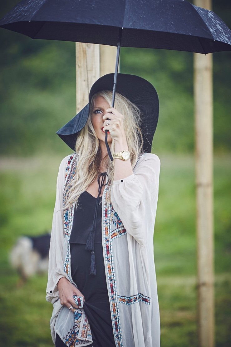 cool female guest with 70's hat obscured by umbrella at a rainy boho wedding in Dorset