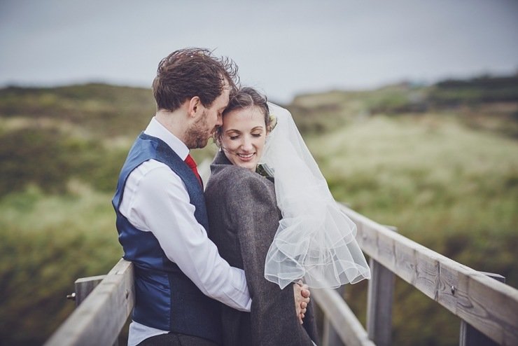 couple keep each other warm during portraits at a wedding in Devon barn at South Milton