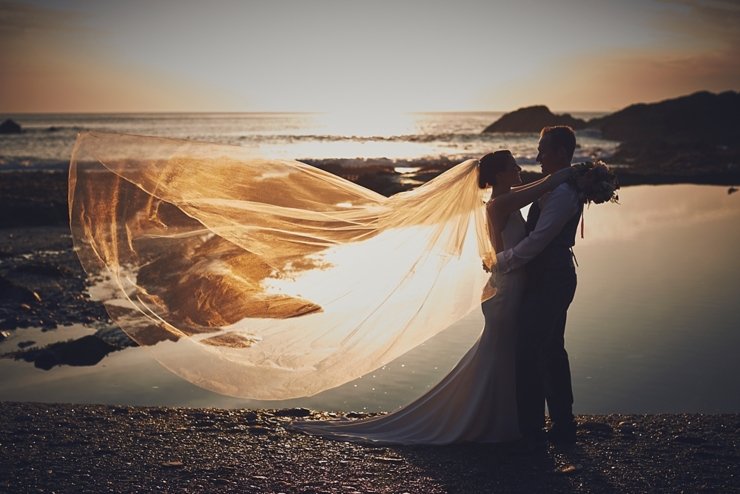 portraits at Tunnels Beaches wedding at sunset with veil blowing