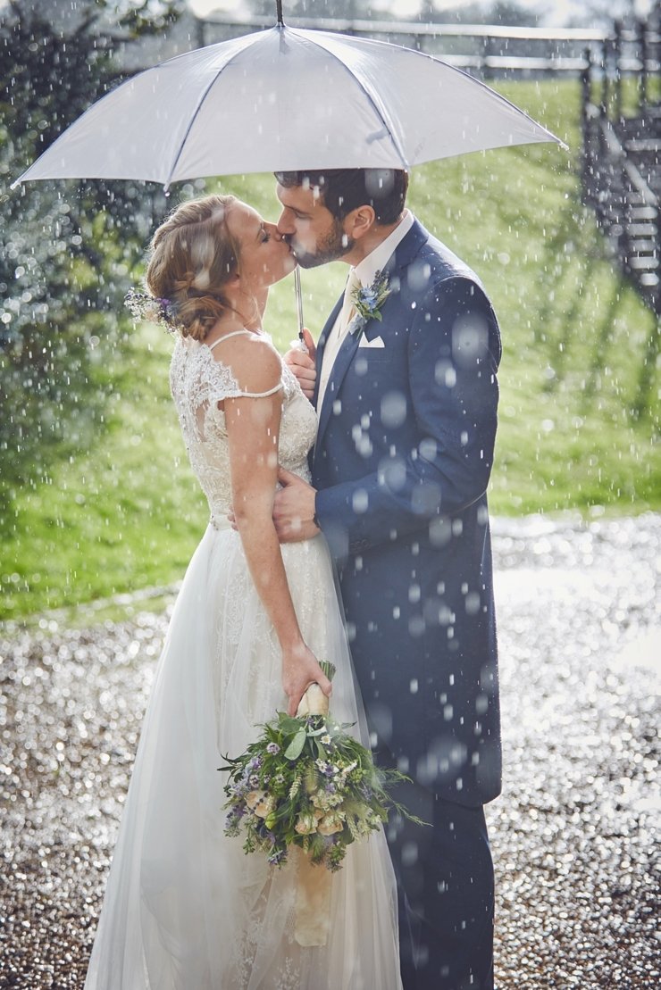 bride and groom kissing under an umbrella in the rain at a Somerset wedding