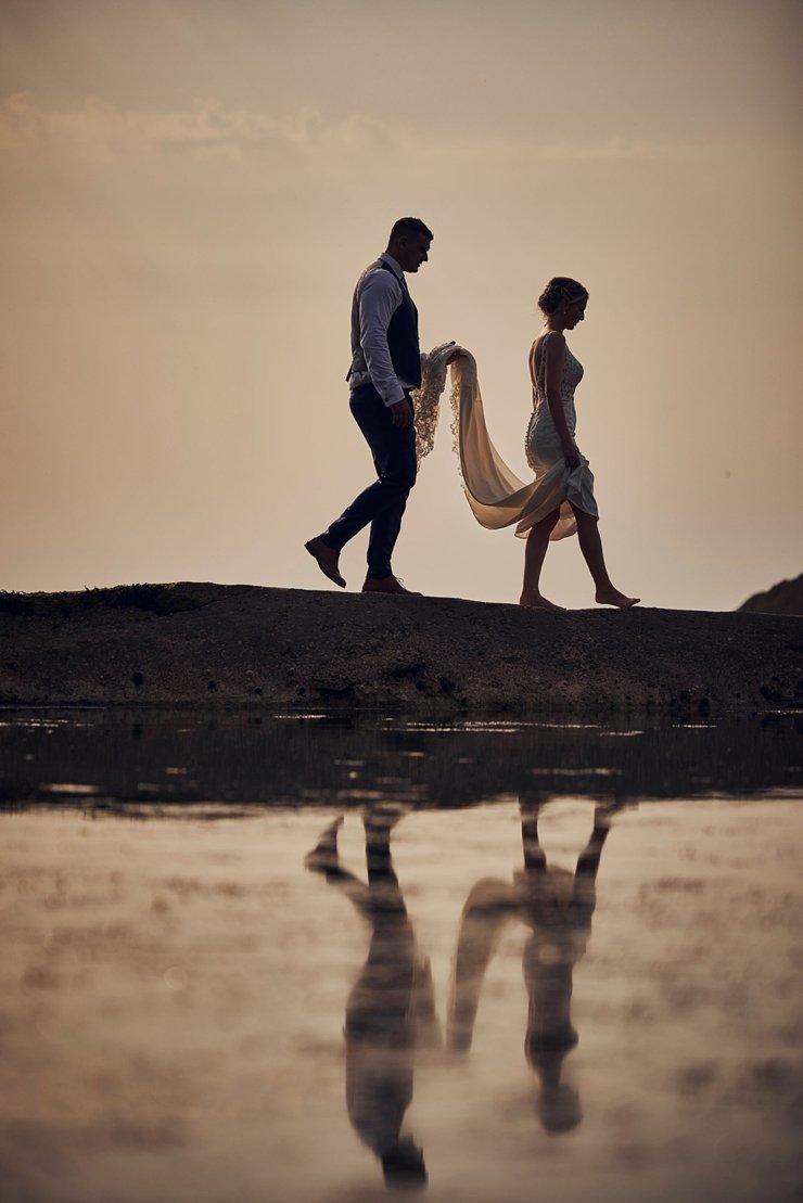 couple walk on tidal pool wall at tunnels beaches