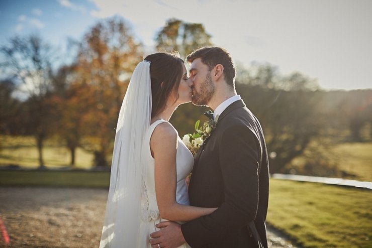 bride and groom kissing in golden hour sunlight at small winter wedding at Rockbeare manor in Devon