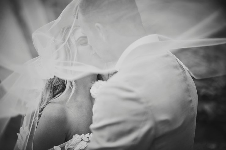 bride and groom kissing under veil at tunnels beaches