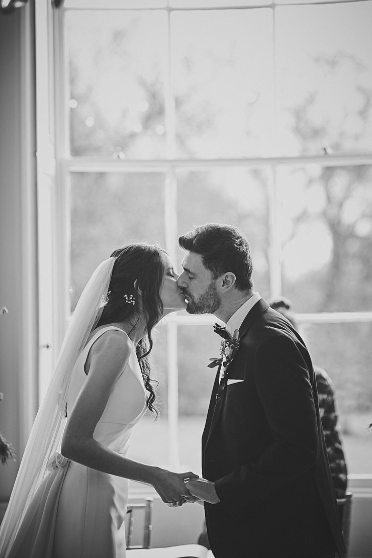 bride and groom first kiss at small wedding at Rockbeare manor in Devon