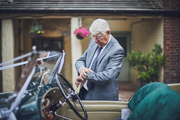 brides grandad checking his watch behind his vintage wedding car