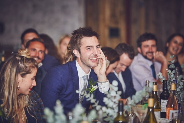 guest laughing at wedding speeches at festival style barn wedding in devon
