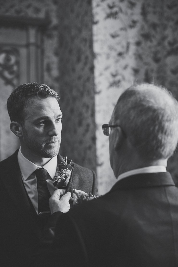 Father of the groom fixes his son's buttonhole at Huntsham Court Devon